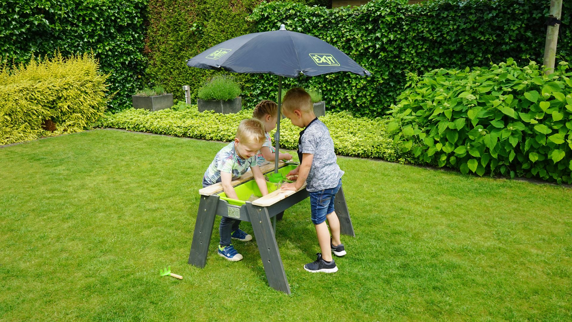 EXIT-Aksent-zand-en-watertafel-met-parasol-en-tuingereedschap