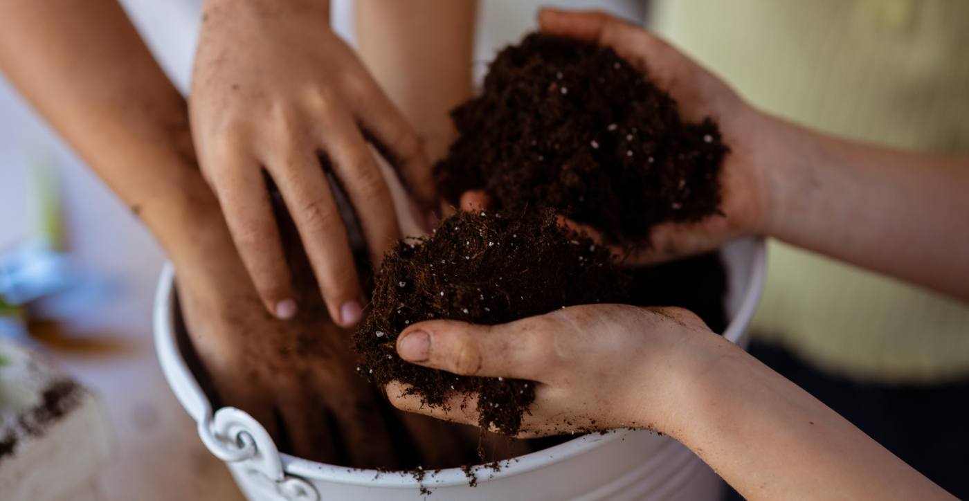 hands full of potting soil from bucket