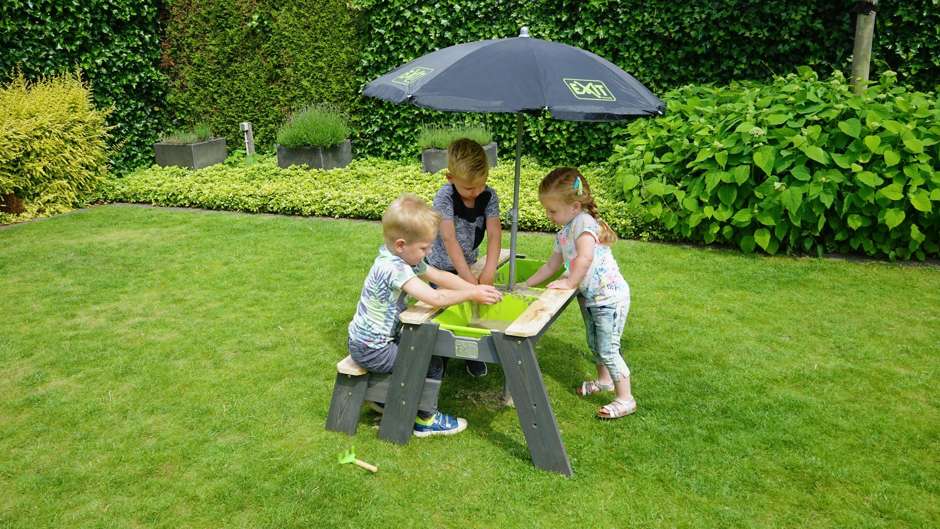 EXIT-Aksent-zand-water-en-picknicktafel-1-bankje-met-parasol-en-tuingereedschap