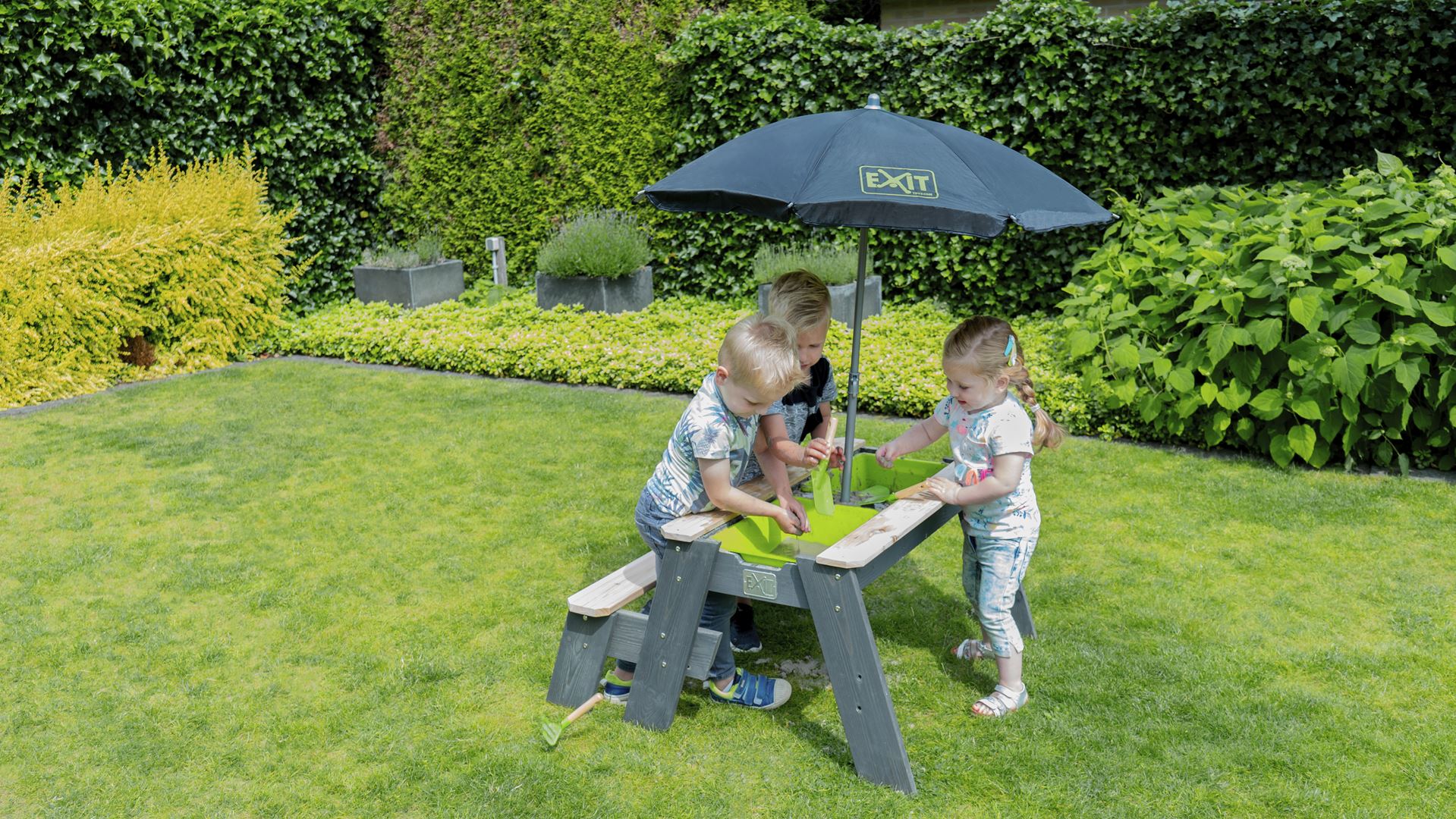 EXIT-Aksent-zand-water-en-picknicktafel-1-bankje-met-parasol-en-tuingereedschap